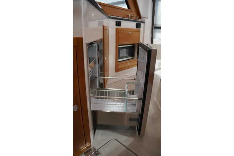 Slide: The Image of 2024 True North 34 yacht interior with open refrigerator and wooden cabinetry. - 3