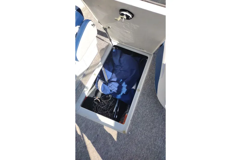 Slide: The Image of Open storage compartment in 2017 Crownline 225 SS boat, containing ropes and blue fabric. - 21