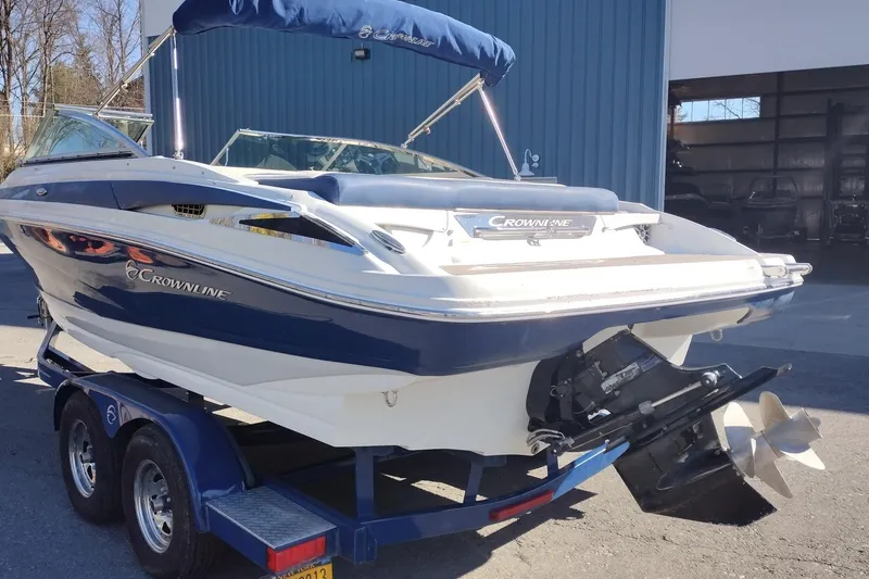 Slide: The Image of 2017 Crownline 225 SS boat on trailer, blue and white, parked outside a building. - 3