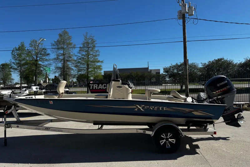 Slide: The Image of 2017 Xpress H20B Bay boat on trailer with Yamaha outboard motor, parked outdoors. - 6