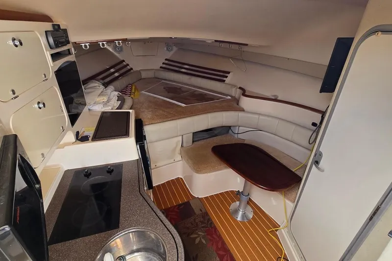 Slide: The Image of Interior of 2006 Grady-White Express 330 boat, featuring cozy seating and compact kitchen area. - 14