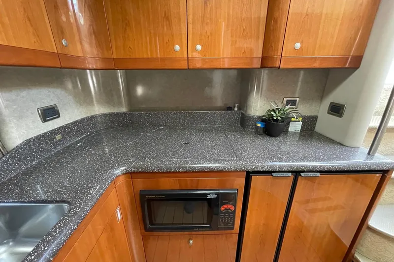 Slide: The Image of 2005 Formula 48 Yacht kitchen with wood cabinets, granite countertop, microwave, and mini fridge. - 12