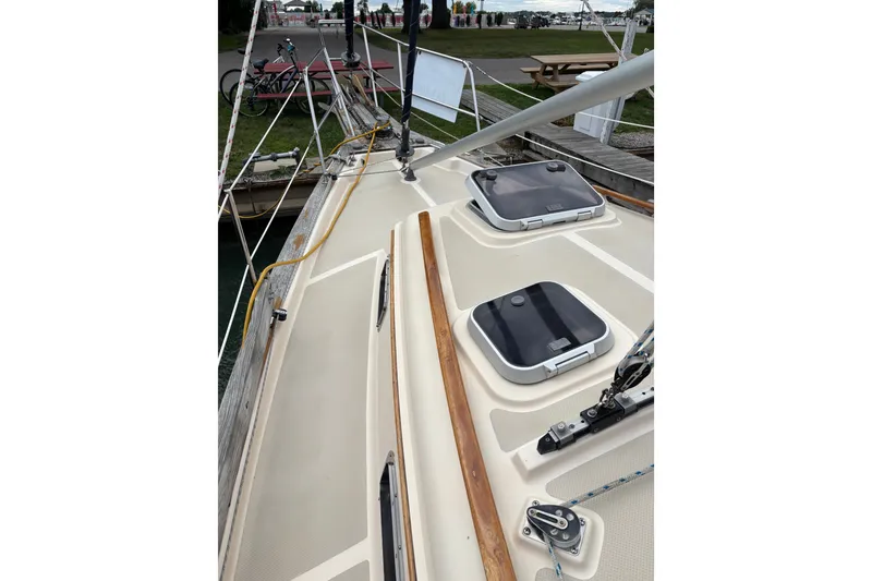Slide: The Image of 1994 Island Packet 32 sailboat deck with hatches and rigging at a marina. - 12