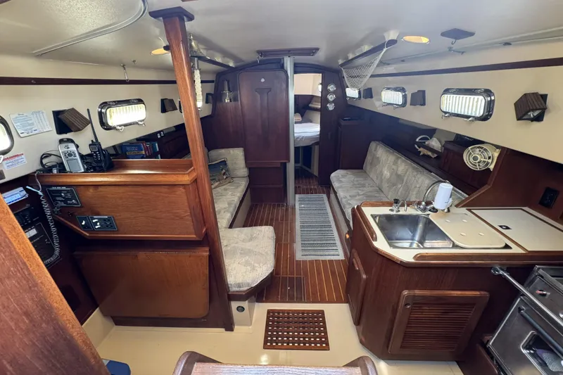Slide: The Image of Interior of a 1994 Island Packet 32 sailboat, featuring cozy seating and a compact kitchen. - 11