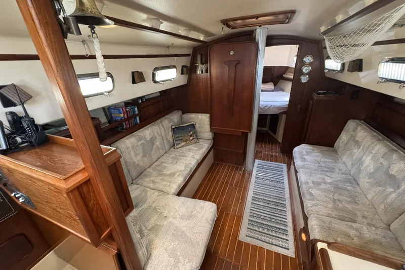 Slide: The Image of Interior of a 1994 Island Packet 32 sailboat, featuring cozy seating and wooden accents. - 12
