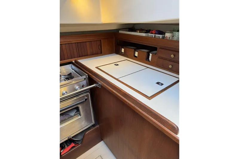 Slide: The Image of 1994 Island Packet 32 yacht galley with stove, wooden cabinetry, and storage compartments. - 15