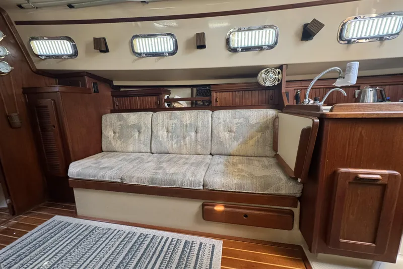 Slide: The Image of Interior of a 1994 Island Packet 32 sailboat with cushioned seating and wooden cabinetry. - 21
