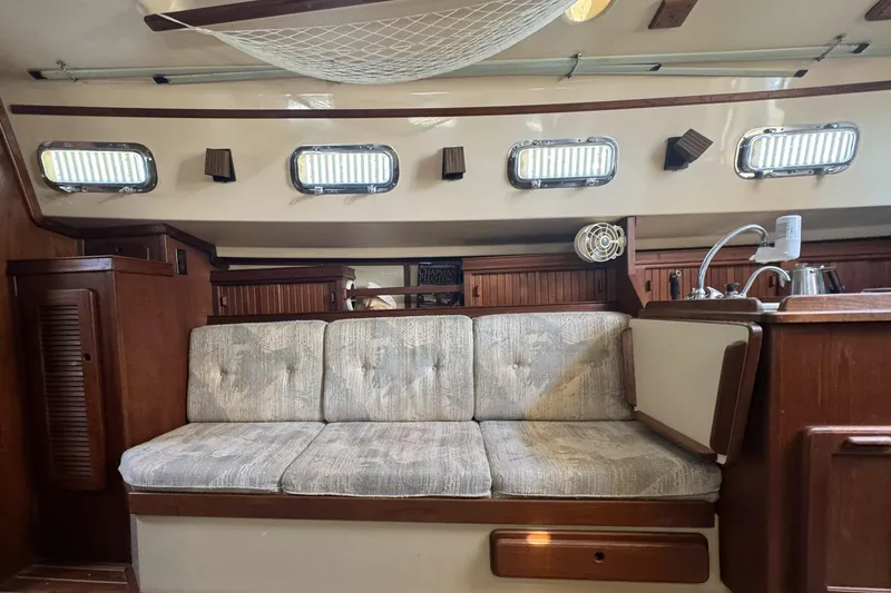 Slide: The Image of Interior of a 1994 Island Packet 32 sailboat with cushioned seating and wooden cabinetry. - 22