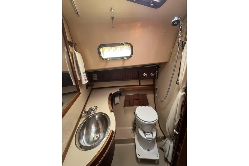 Slide: The Image of 1994 Island Packet 32 yacht bathroom with sink, toilet, and showerhead. - 24