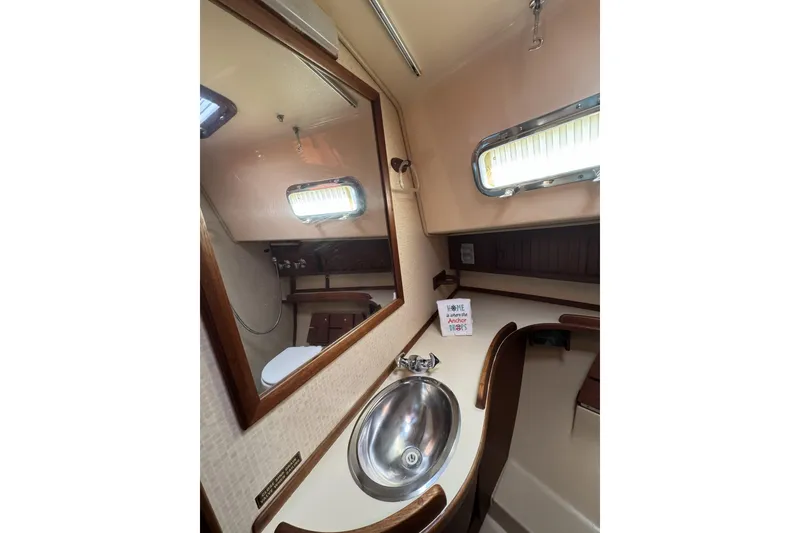 Slide: The Image of 1994 Island Packet 32 yacht bathroom with sink, mirror, and porthole window. - 25