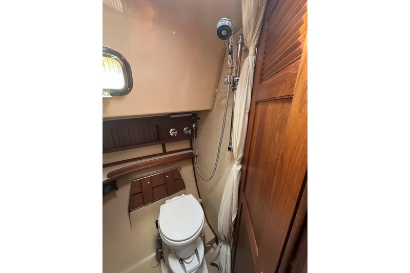 Slide: The Image of 1994 Island Packet 32 yacht bathroom with shower and toilet, featuring wooden accents. - 26