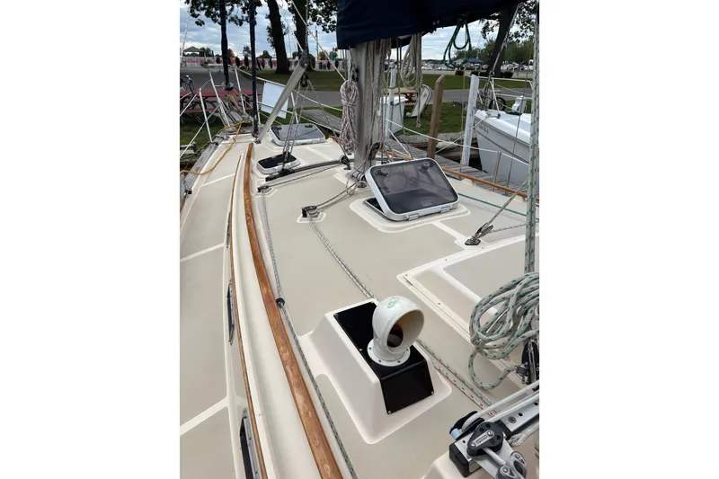 Slide: The Image of 1994 Island Packet 32 sailboat deck with ropes and hatch, docked in a marina. - 11