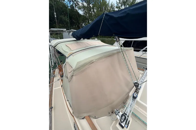 Slide: The Image of 1994 Island Packet 32 sailboat with beige canvas cover and blue sail, docked. - 21