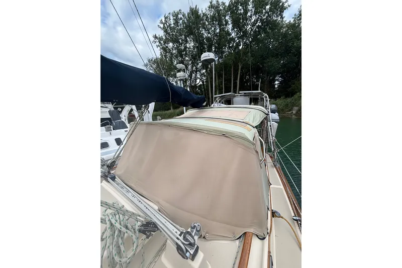 Slide: The Image of 1994 Island Packet 32 sailboat docked, featuring beige canvas cover and rigging. - 20