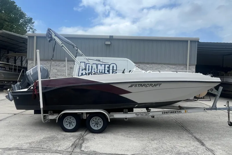 The Image of 2021 Starcraft SVX 211 OB boat on trailer, parked outside a warehouse. - 1
