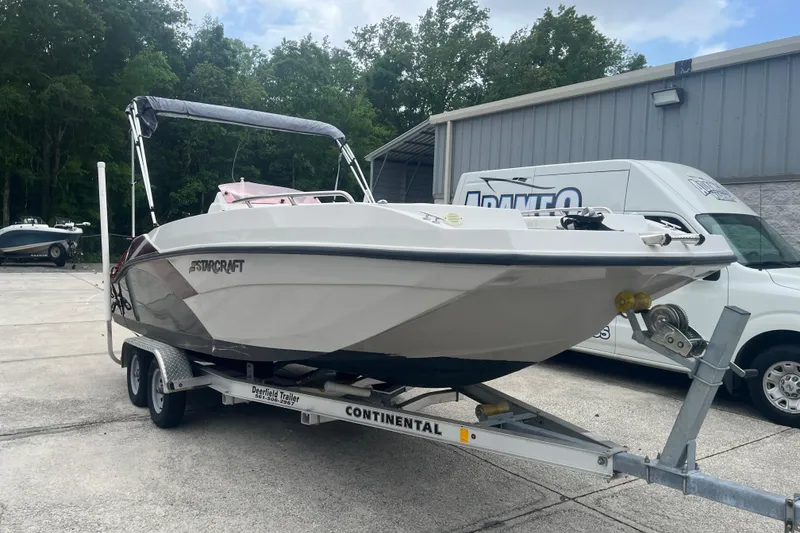 Slide: The Image of 2021 Starcraft SVX 211 OB boat on trailer, parked outdoors near a building. - 7