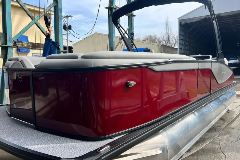 Slide: The Image of 2026 Harris Sunliner 230 pontoon boat with red exterior and gray seating, docked outdoors. - 10