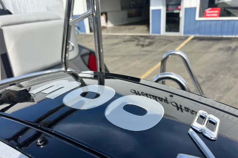 Slide: The Image of 2026 Harris Sunliner 230 boat detail with reflective surface and ladder in a marina setting. - 19