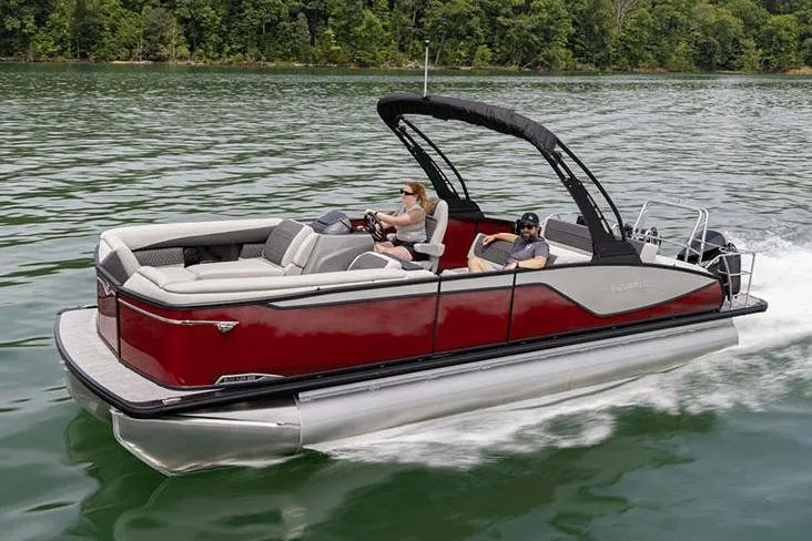 Slide: The Image of Manufacturer Provided Image: 2026 Harris Sunliner 230 pontoon boat cruising on a lake with lush green trees. - 2