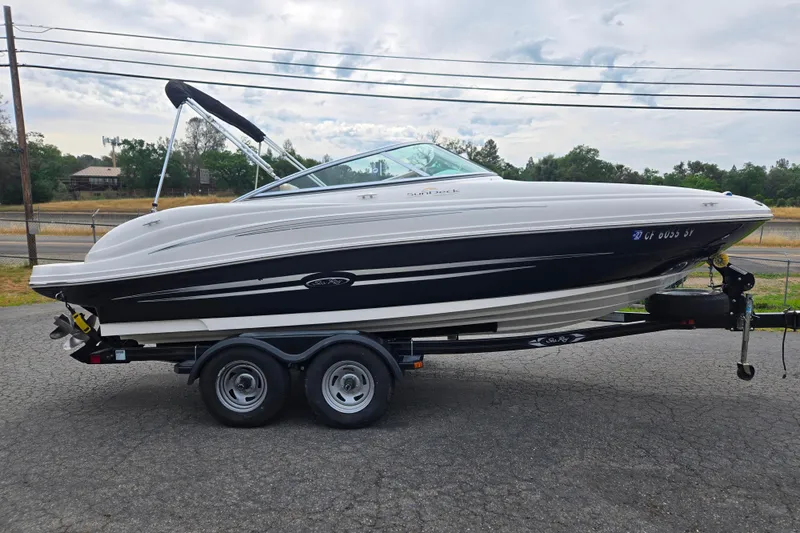 The Image of 2011 Sea Ray 200 Sundeck boat on trailer, parked outdoors. - 1