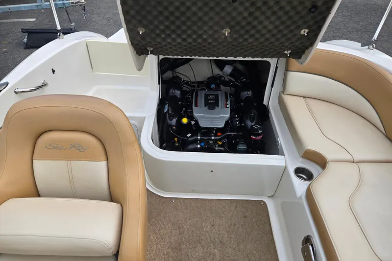 Slide: The Image of 2011 Sea Ray 200 Sundeck interior with open engine compartment and beige seating. - 19