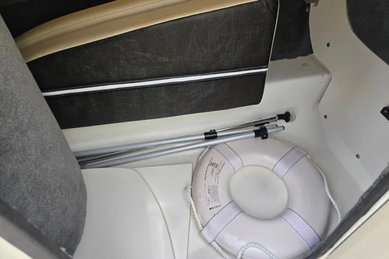 Slide: The Image of Storage compartment in a 2011 Sea Ray 200 Sundeck with life preserver and poles. - 23