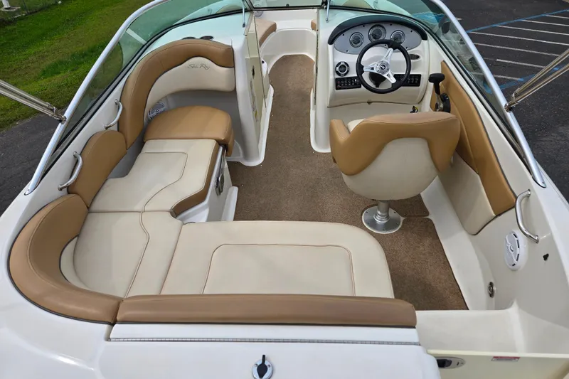 Slide: The Image of 2011 Sea Ray 200 Sundeck interior with beige seating and steering console. - 6