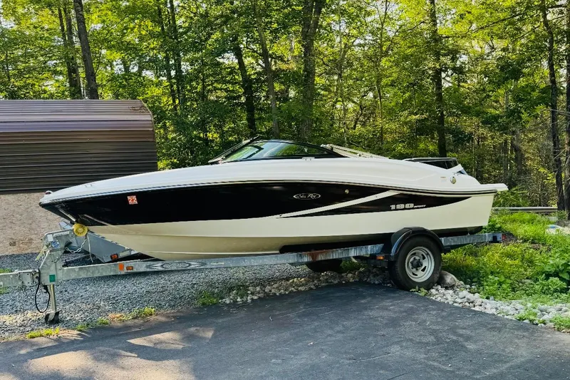 The Image of 2013 Sea Ray 190 Sport boat on trailer in wooded area. - 0