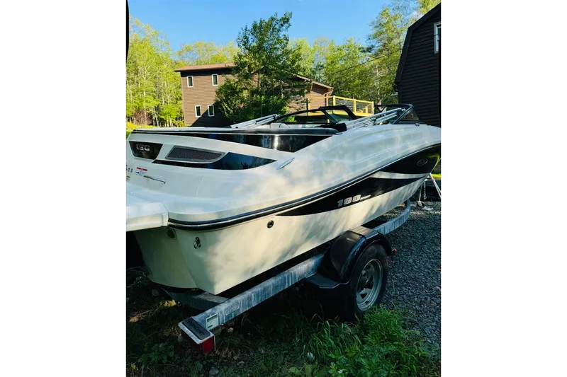 Slide: The Image of 2013 Sea Ray 190 Sport boat on trailer, parked outdoors near trees and buildings. - 1