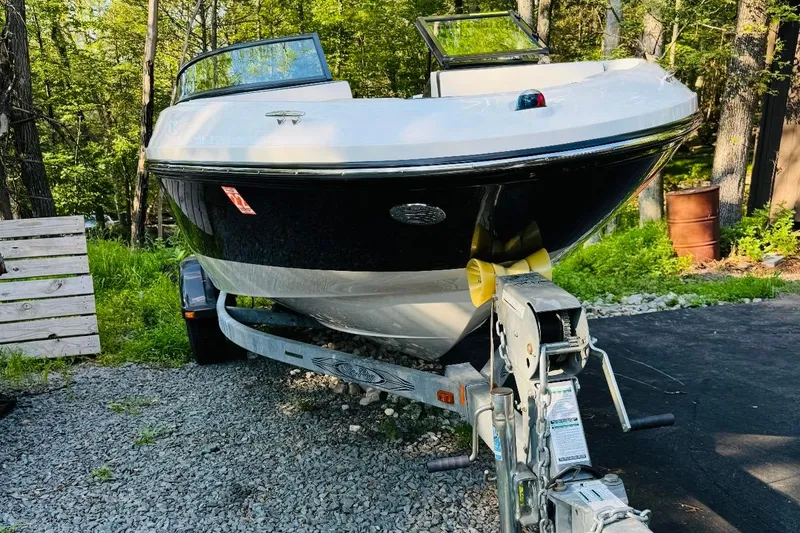 Slide: The Image of 2013 Sea Ray 190 Sport boat on trailer in wooded area. - 11