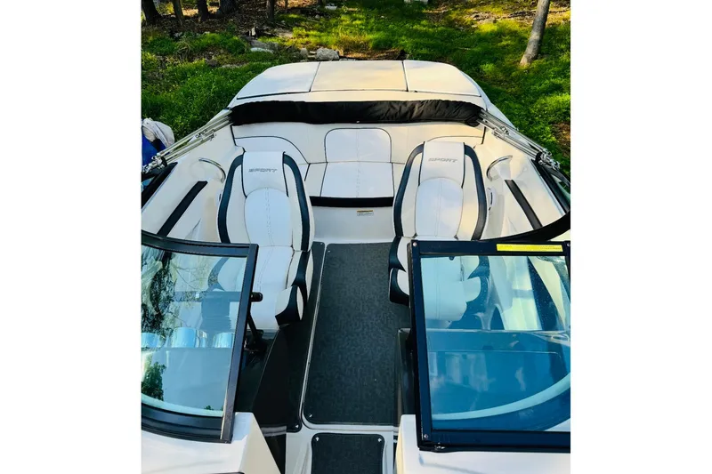Slide: The Image of 2013 Sea Ray 190 Sport boat interior with white seating and glass windshields. - 2