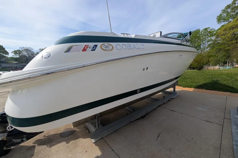 Slide: The Image of 2000 Cobalt 292 boat on display, white hull with green accents, parked outdoors. - 17