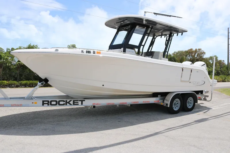 The Image of 2021 Robalo R272 Center Console boat on a Rocket trailer, parked outdoors. - 1