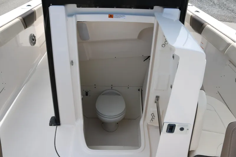 Slide: The Image of 2021 Robalo R272 Center Console boat interior with compact marine toilet. - 13