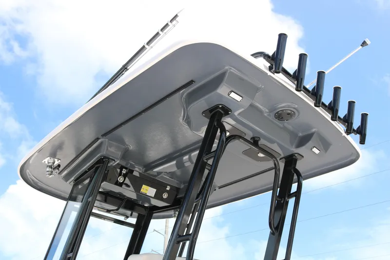 Slide: The Image of 2021 Robalo R272 Center Console boat's T-top with rod holders against blue sky. - 6