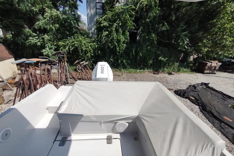 Slide: The Image of RYCK 280 boat, 2023 model, covered and parked outdoors near greenery and equipment. - 53