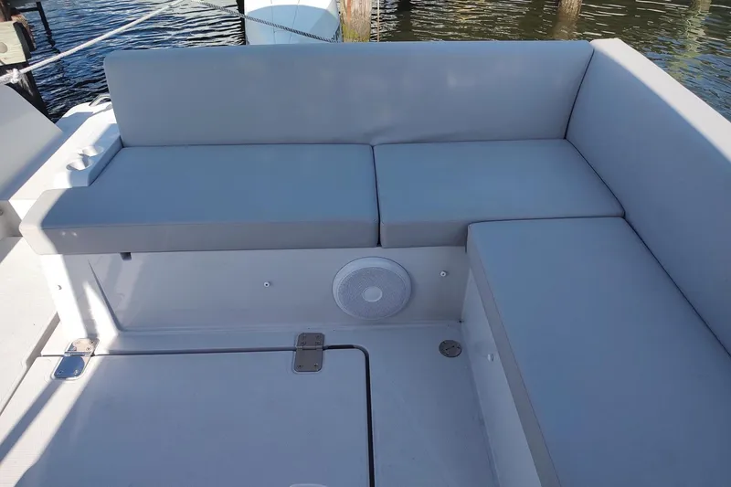 Slide: The Image of RYCK 280 boat seating area, 2023 model, with gray cushions and a speaker. - 14