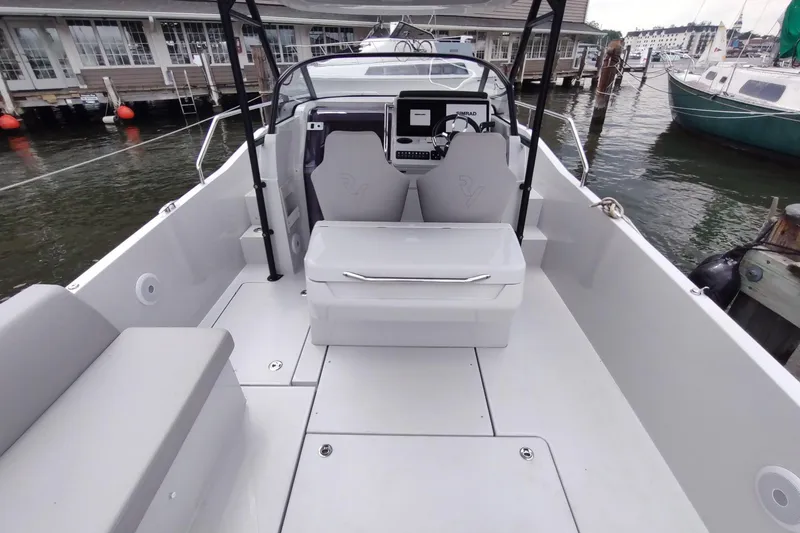 Slide: The Image of 2023 RYCK 280 boat interior with modern seating and control panel at a marina. - 15