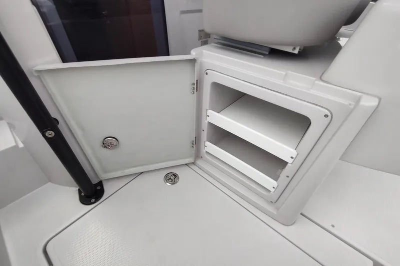 Slide: The Image of Open storage compartment on a 2023 RYCK 280 boat, featuring white shelves and a closed door. - 34