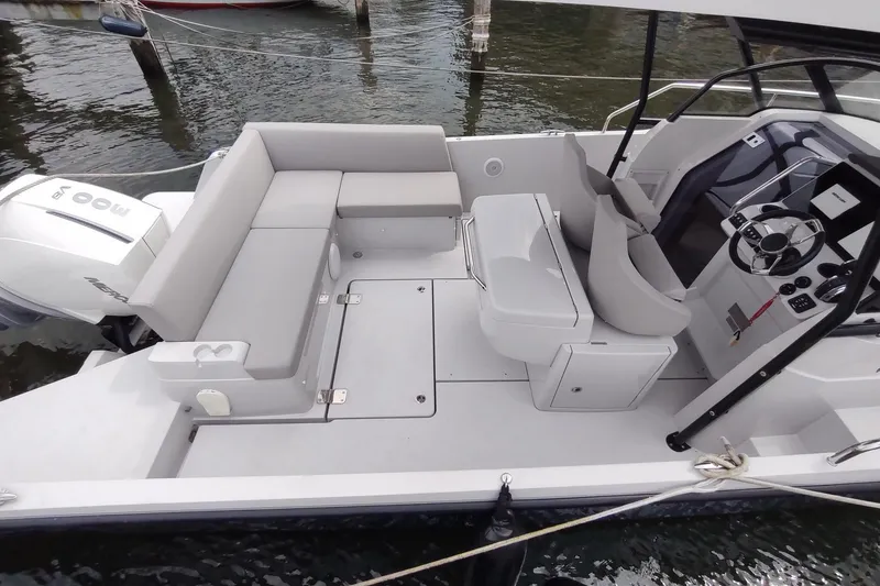 Slide: The Image of 2023 RYCK 280 boat interior with seating and steering console, docked on water. - 11
