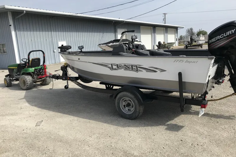 Slide: The Image of 2017 Lund 1775 Impact SS boat on trailer, parked near a metal building. - 9