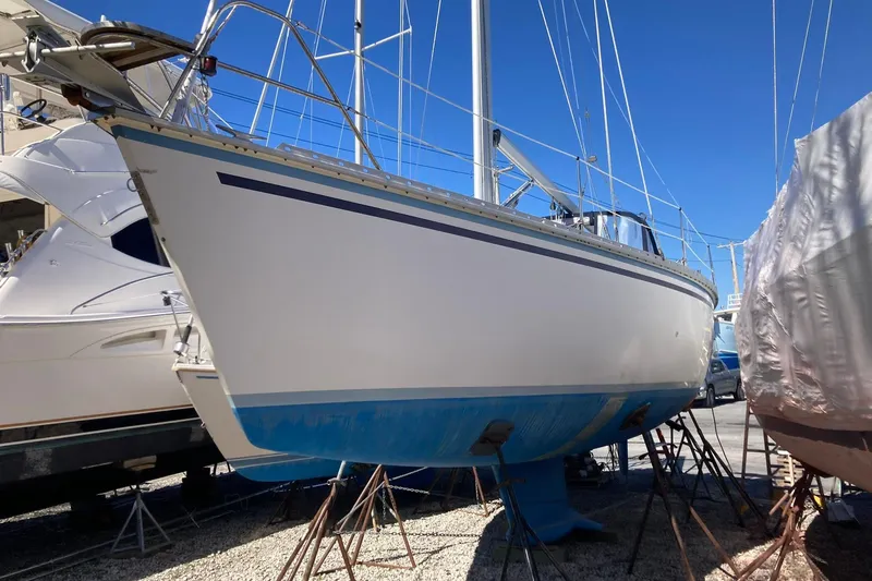 The Image of 1987 Hunter Legend 35 sailboat on stands in a marina, clear blue sky background. - 0