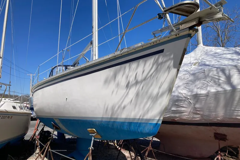 Slide: The Image of 1987 Hunter Legend 35 sailboat on land, blue and white hull, clear sky background. - 1