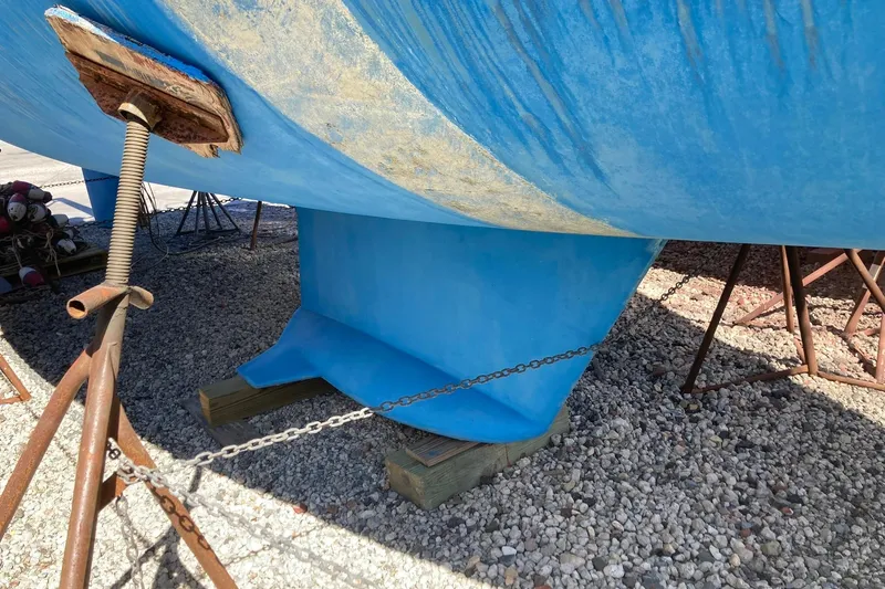 Slide: The Image of 1987 Hunter Legend 35 sailboat keel on gravel, supported by stands and chains. - 3