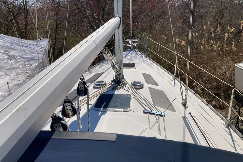 Slide: The Image of 1987 Hunter Legend 35 sailboat deck with rigging and hatches, surrounded by trees. - 4
