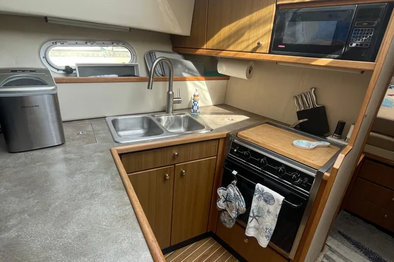 Slide: The Image of 2001 Bayliner 3388 Command Bridge Motoryacht kitchen with sink, stove, and microwave. - 17