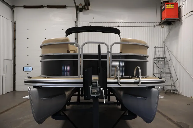 Slide: The Image of 2022 Harris Cruiser LX180 pontoon boat in a spacious indoor storage facility. - 2