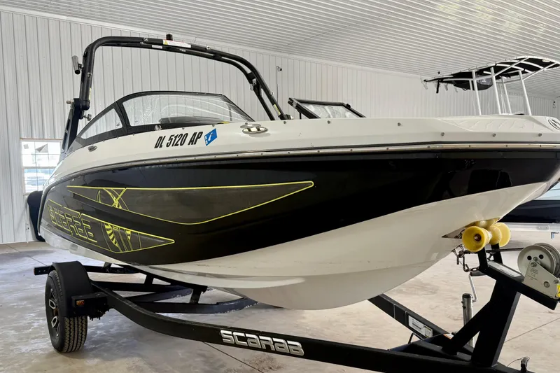 Slide: The Image of 2023 Scarab 195 ID boat on trailer in spacious indoor garage. - 4