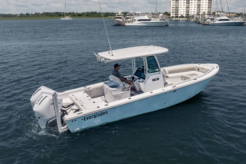 Slide: The Image of 2026 Everglades 273 Center Console boat cruising on open water near marina. - 2