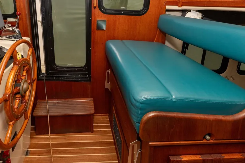 Slide: The Image of Interior of 2002 Nordic Tug 32 with wooden helm and teal seating. - 2